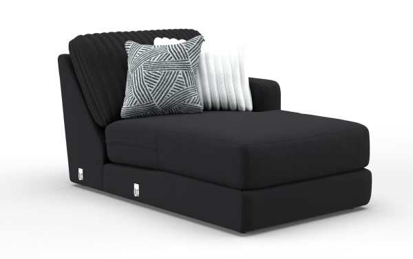 Black modern chaise lounge with soft fabric upholstery, featuring a ribbed backrest, two decorative pillows in white and geometric black-and-white pattern, designed for stylish and comfortable seating.