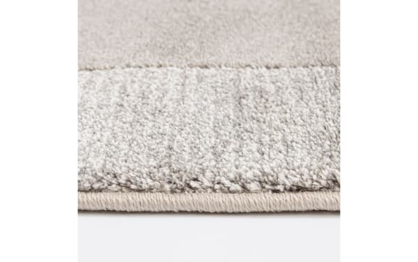 Close-up of the Atlas 5' x 7' Gray Geometric Rug showing plush, thick polypropylene pile with a subtle geometric pattern in gray tones, featuring a tightly woven edge for durability in a transitional style.