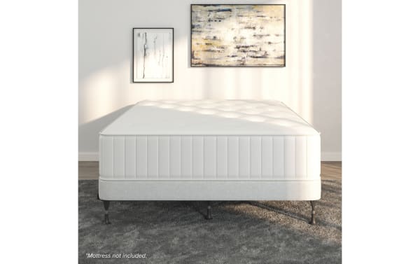 Universal Bed Frame in light gray fabric with durable black steel legs, designed for superior mattress support and bedroom versatility.
