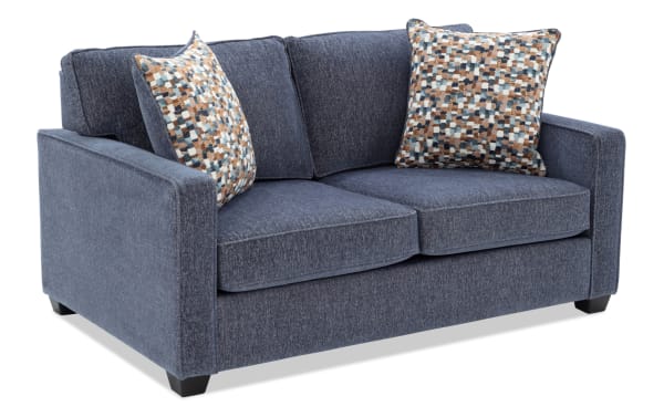 Two-seater navy blue fabric loveseat sofa with textured upholstery, square arms, tapered wooden legs, and two patterned throw pillows in blue, brown, and white.