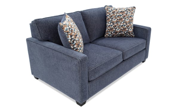 Modern navy blue fabric loveseat sofa with clean lines, plush cushions, and two patterned accent pillows, ideal for contemporary living rooms.