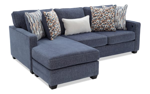 Modern navy blue fabric sectional sofa with chaise lounge, textured upholstery, and multicolored patterned throw pillows for living room seating.