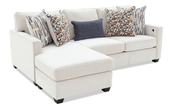 Modern beige fabric sectional sofa with chaise lounge, featuring patterned and solid throw pillows, ideal for living room seating.