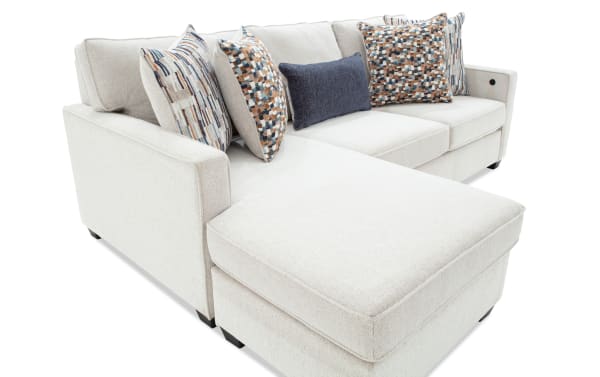 Modern beige fabric sectional sofa with chaise lounge, patterned throw pillows, and dark wooden legs, ideal for contemporary living rooms.