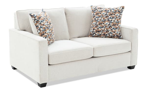 Two-seater beige fabric loveseat sofa with square armrests and patterned blue, brown, and white throw pillows, modern design.