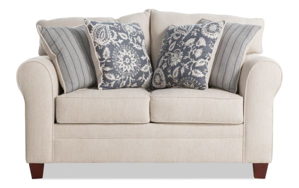 Portland Beige 65'' Loveseat in transitional style with soft beige polyester fabric, rolled arms, wooden legs, and four decorative blue-patterned accent pillows.