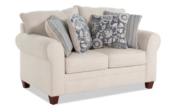 Portland Beige 65'' Loveseat with soft polyester fabric upholstery, transitional style, beige color, rolled arms, wooden legs, and four decorative blue patterned pillows.