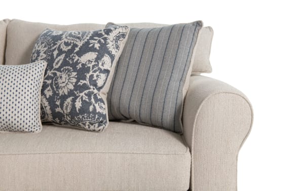 Beige Portland 85'' transitional sofa with soft polyester fabric upholstery, rounded armrest, and three decorative accent pillows in blue and beige patterns.