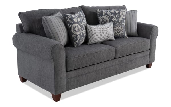 Portland Gray 85'' transitional sofa with soft gray polyester fabric upholstery, rolled arms, tapered wooden legs, and five decorative accent pillows.