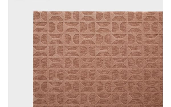 Close-up of a textured brown carpet with a geometric pattern of squares and quarter circles, showcasing its soft fabric and modern design.