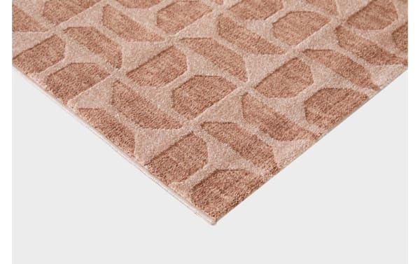 Corner view of a textured area rug with a geometric pattern in shades of beige and brown, highlighting its woven fabric and flat edge.