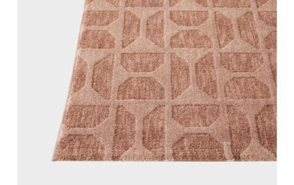 Close-up of a textured area rug with a geometric pattern in shades of beige and brown, featuring octagonal and rectangular shapes.
