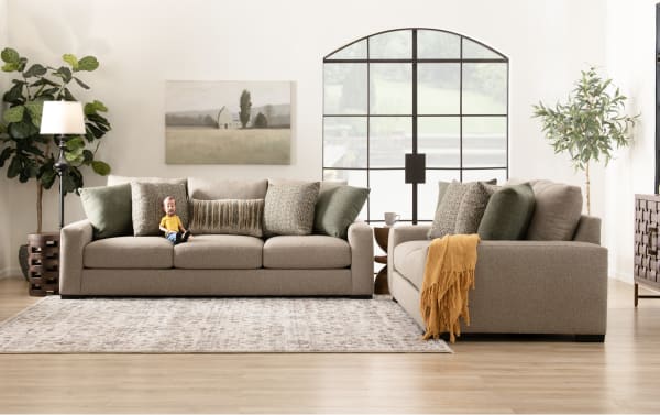 Transitional-style living room with gray fabric polyester sofas from the Camden collection, featuring plush cushions, patterned pillows, and a mustard throw.
