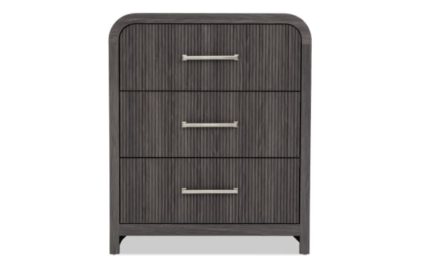 Dark gray wooden three-drawer chest with vertical grooves and silver metal handles, modern bedroom storage furniture.