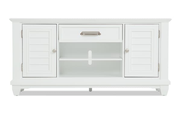 White wooden TV stand with two shutter-style cabinet doors, a central open shelf with cable management hole, and a top drawer with metal handle.