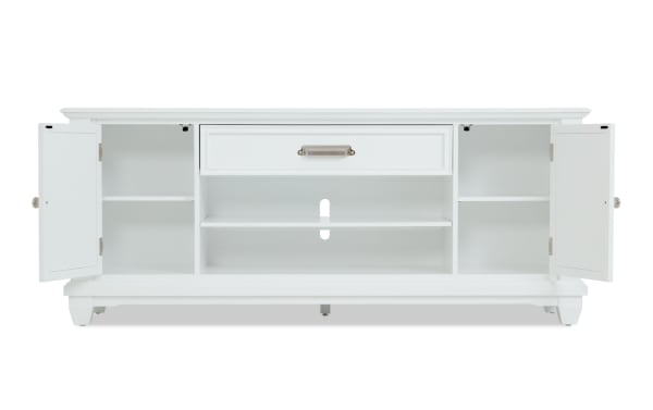 White wooden TV stand with two open cabinet doors, adjustable shelves, and a central drawer with a brushed metal handle, designed for media storage.