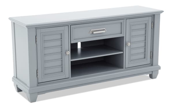 Gray wooden TV stand with two louvered doors, one center drawer with metal handle, and open shelving for media devices, modern style.