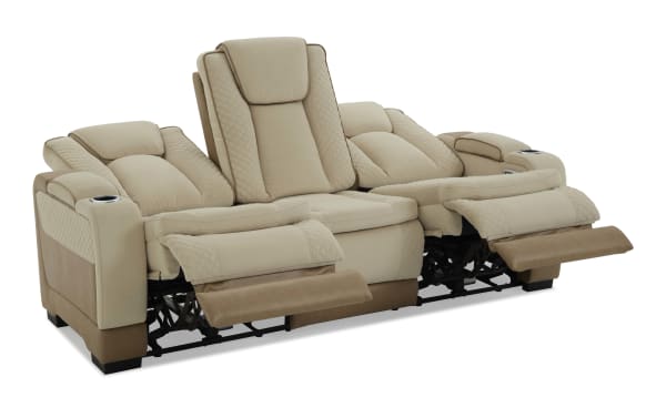 Beige and tan leather reclining loveseat with quilted stitching, padded armrests, cup holders, and adjustable footrests for home theater comfort.