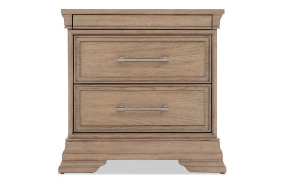 Wooden nightstand with a light brown finish, featuring two spacious drawers with metal handles and classic molding details.