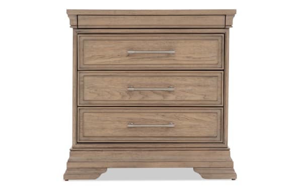 Three-drawer wooden nightstand with a light brown finish, metal handles, and classic beveled edges, ideal for bedroom storage.
