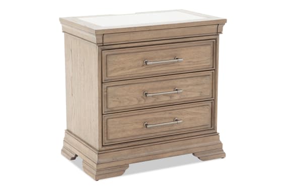 Three-drawer wooden nightstand with a light oak finish, metal handles, and decorative molding, ideal for bedroom storage.