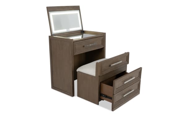 Compact wooden vanity set with a lighted mirror, cushioned stool, and storage drawer, featuring a modern brown finish and metal handles.