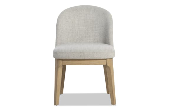Modern dining chair with light gray upholstered fabric seat and backrest, supported by natural oak wood legs, suitable for contemporary interiors.