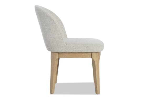 Side view of a modern dining chair with light gray upholstered fabric seat and backrest, supported by natural oak wood legs.