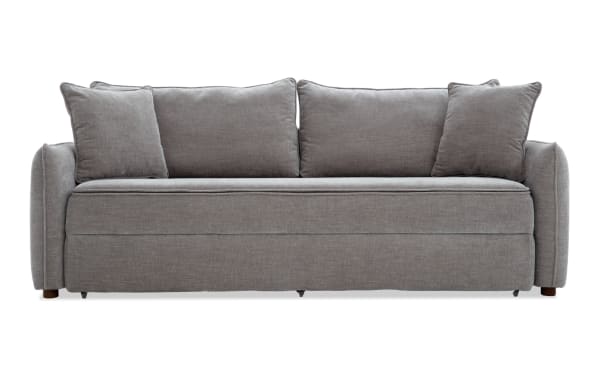 Modern gray fabric sofa with three large back cushions and two smaller side pillows, featuring a clean, minimalist design and soft upholstery.