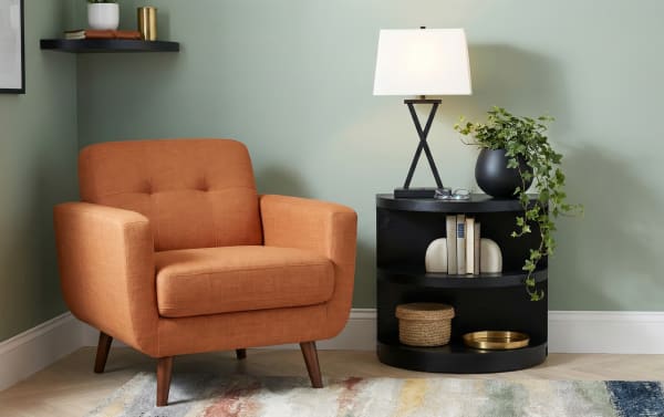 Contemporary Hampton Black Half Oval End Table in gray MDF with two shelves, paired with an orange polyester fabric armchair in a living room setting.