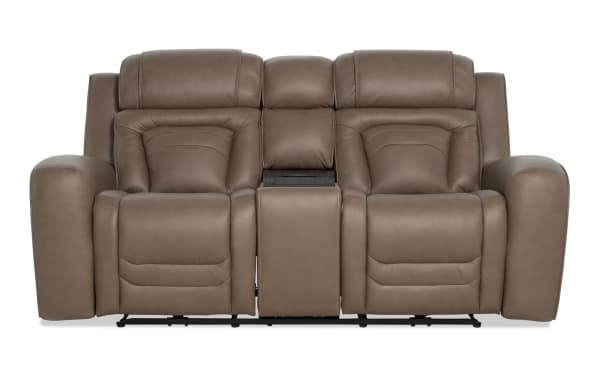Modern brown leather reclining loveseat with padded armrests, high backrests, and a central console for storage or cup holders, ideal for living room seating.