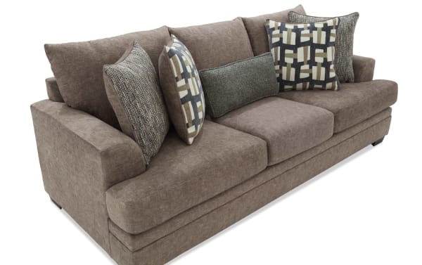 Brown fabric sofa with plush cushions and patterned throw pillows, featuring a modern design with wide armrests and soft upholstery.