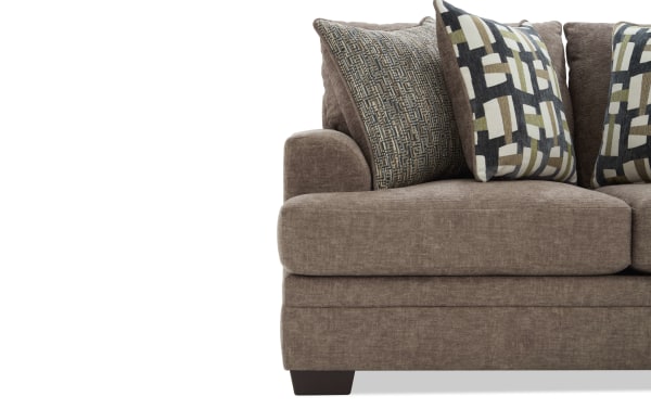 Brown fabric sectional sofa with plush cushions and patterned throw pillows, featuring dark wooden block legs and a modern design.