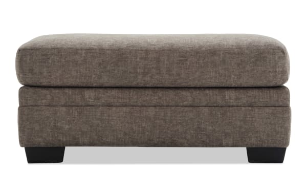 Rectangular brown fabric ottoman with plush cushioned top and dark wooden block legs, suitable for living room seating or footrest.