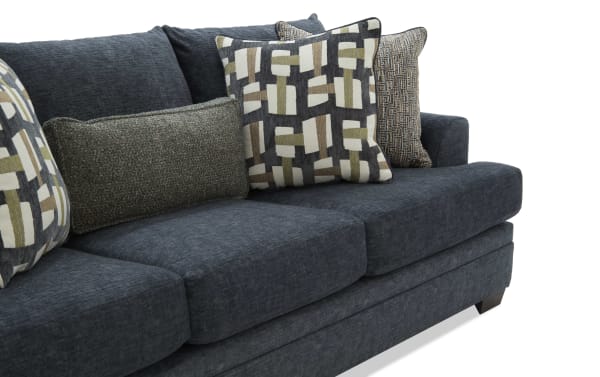 Dark gray fabric sofa with plush cushions and patterned throw pillows in neutral tones, showcasing modern living room furniture design.