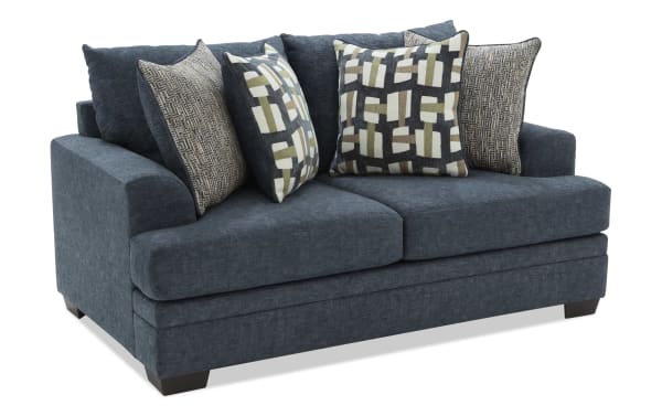 Dark blue fabric loveseat sofa with four patterned throw pillows, featuring plush cushions and wooden block legs, suitable for modern living rooms.