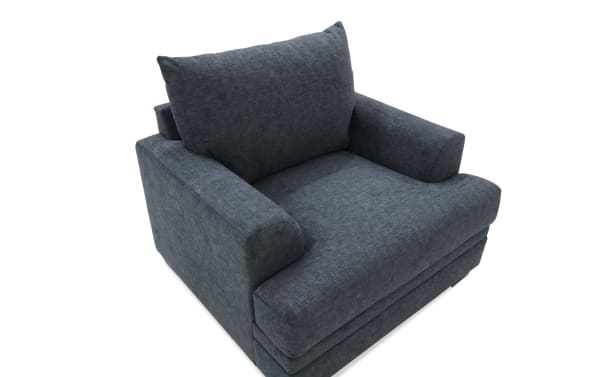 Dark gray upholstered armchair with thick cushioned seat and backrest, wide armrests, and a modern, cozy design.