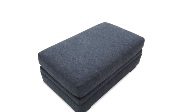 Rectangular dark gray upholstered fabric ottoman with a cushioned top and layered design, suitable for living room seating or footrest.