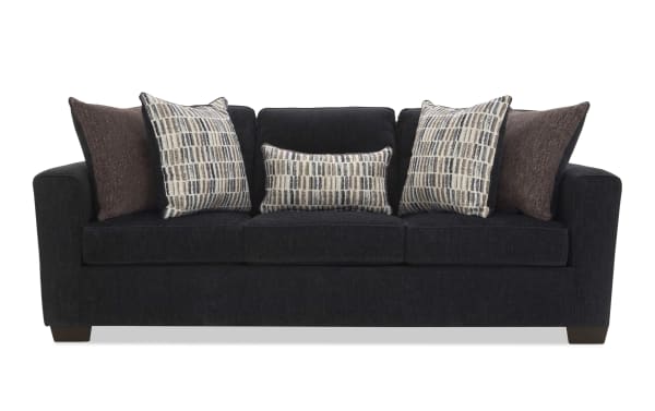 Dark gray fabric sofa with three seat cushions and five decorative pillows in brown and patterned beige, ideal for modern living rooms.