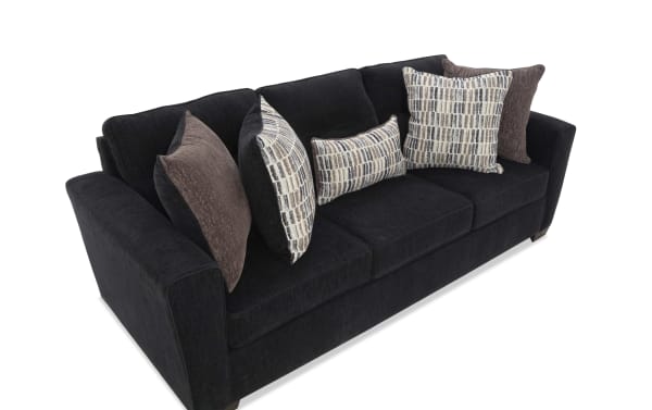 Black fabric sofa with three seat cushions and six decorative pillows in brown and patterned beige tones, featuring a modern, plush design.