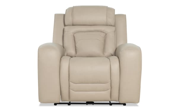 Beige leather recliner chair with padded armrests and cushioned backrest, designed for comfort and relaxation in living spaces.