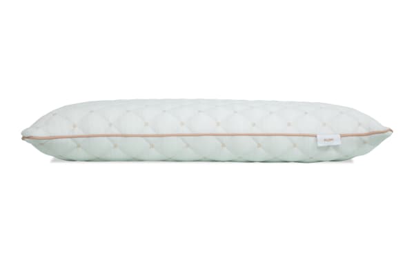 White quilted rectangular pillow with diamond stitching pattern, beige piping along the edge, and a small tag labeled "PLUSH" on the side.