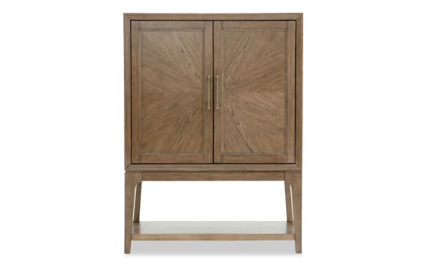 Wooden cabinet with sunburst-patterned double doors, brass handles, and an open lower shelf, featuring a mid-century modern style.