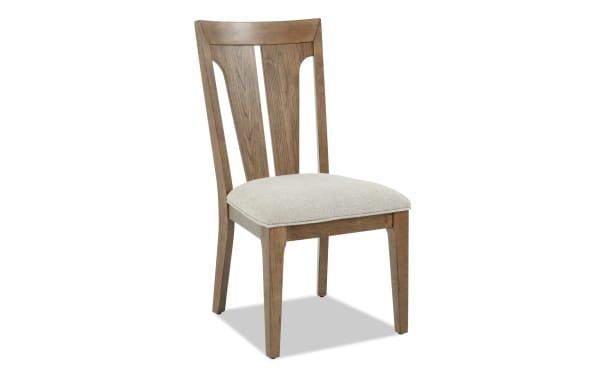 Wooden dining chair with beige upholstered cushioned seat, tapered legs, and slatted backrest in a natural finish, suitable for kitchen or dining room.