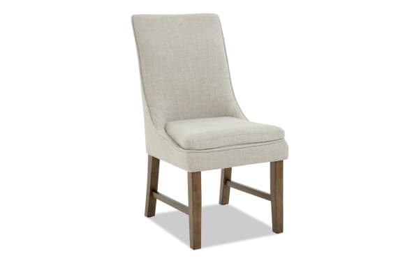Upholstered dining chair with beige textured fabric, cushioned seat, curved backrest, and wooden legs in a natural finish.