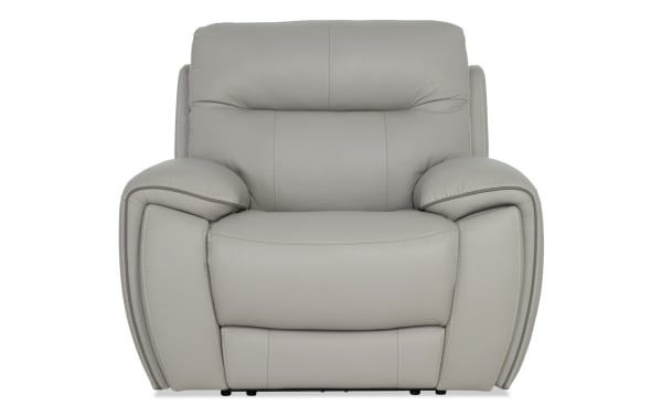 Modern gray leather recliner chair with plush cushioning, wide armrests, and detailed stitching, designed for living room comfort.