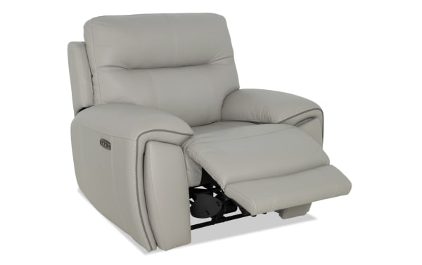Gray leather power recliner chair with padded armrests and backrest, featuring an extended footrest and visible control buttons on the side.