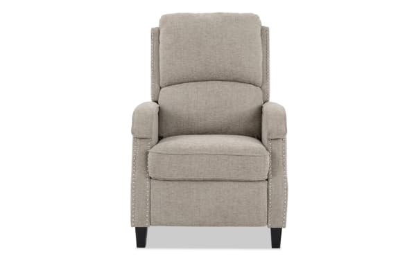 Beige fabric upholstered recliner chair with cushioned backrest and armrests, accented with silver nailhead trim and dark wooden legs.