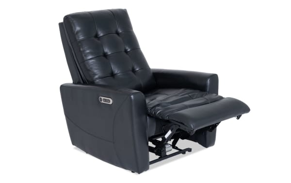 Black leather power recliner chair with tufted backrest and padded armrests, featuring an extended footrest and side control panel for adjustable comfort.