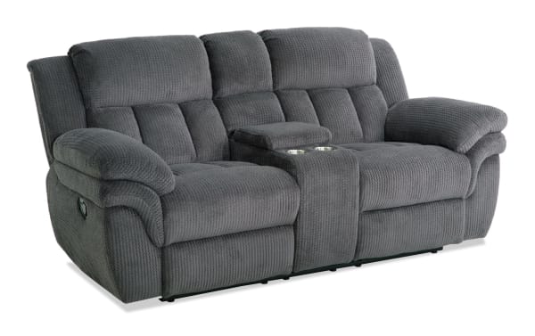 Gray fabric reclining loveseat with plush padded armrests, segmented back cushions, and a center console with cup holders, designed for comfort and relaxation.
